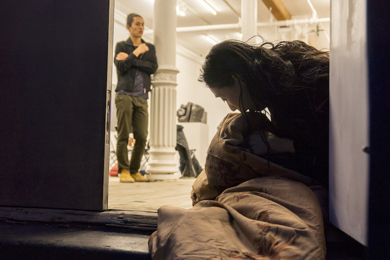 Eiko wrapped up in a blanket while she sits in a doorway